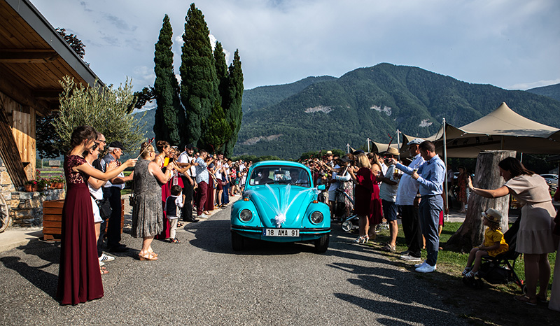 Mise en valeur en plan large de l'arrivée de la voiture des mariés.