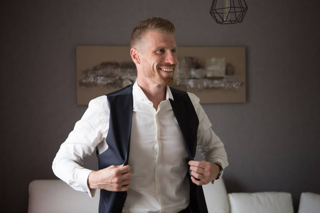 Une photo représentant le marié qui met sa veste.