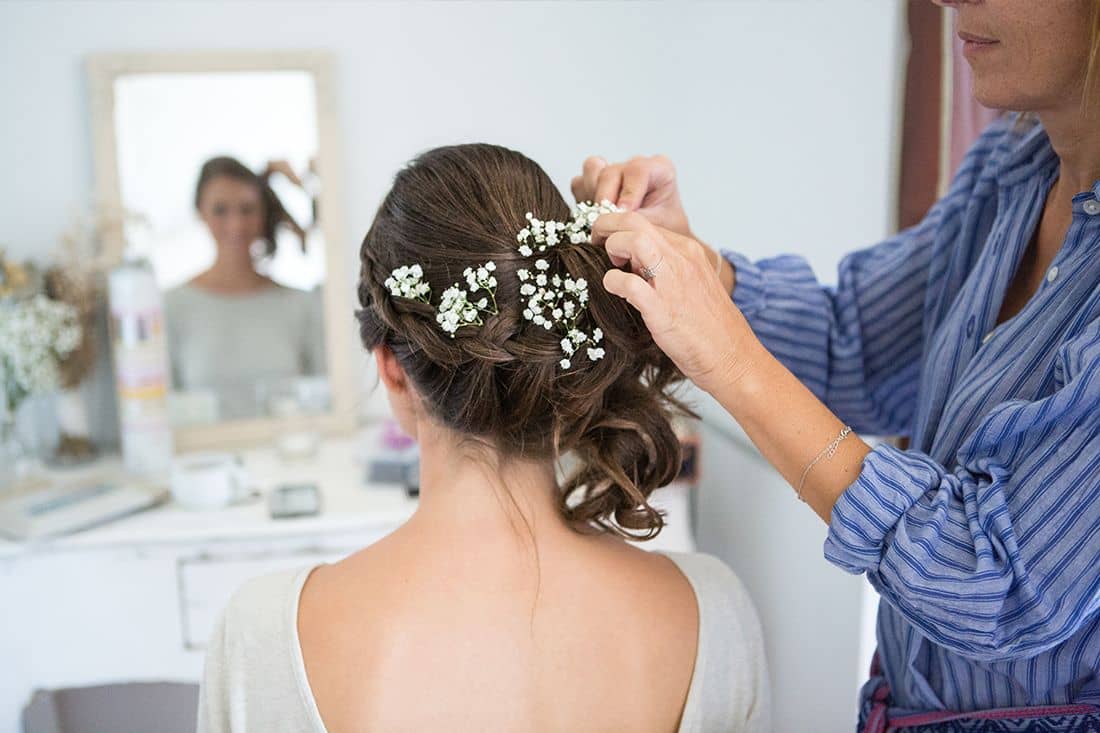 La coiffeuse pose la couronne de fleurs